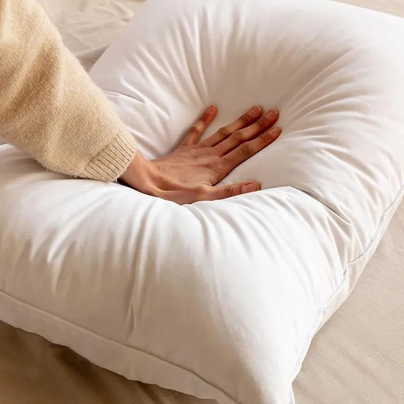 Hand resting on a white pillow with a person wearing a beige sweater.