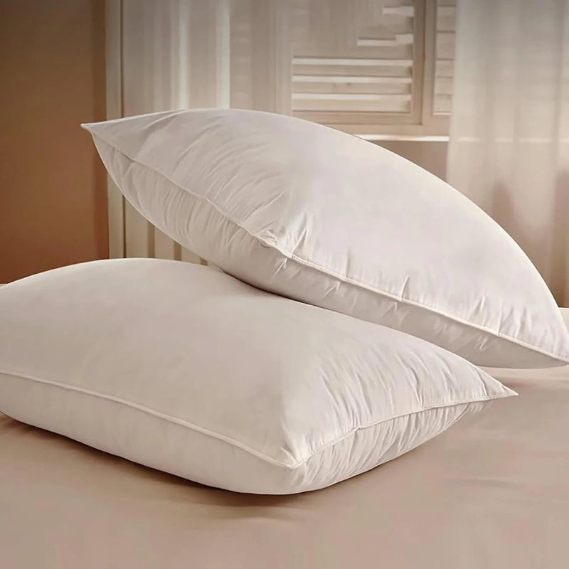 Two white pillows on a bed with a neutral background
